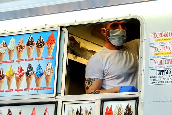 a Mr. Frostee guy in a face mask serves some ice cream